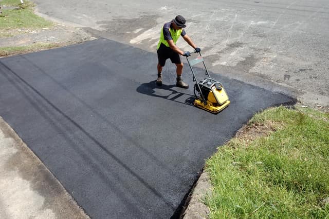 A freshly laid asphalt driveway being compacted with a plate compactor on the Central Coast