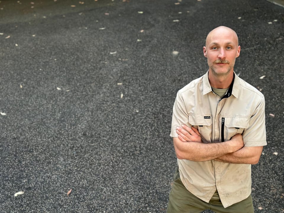 Nathan standing with arms folded on a finished asphalt driveway in a hi-vis work shirt